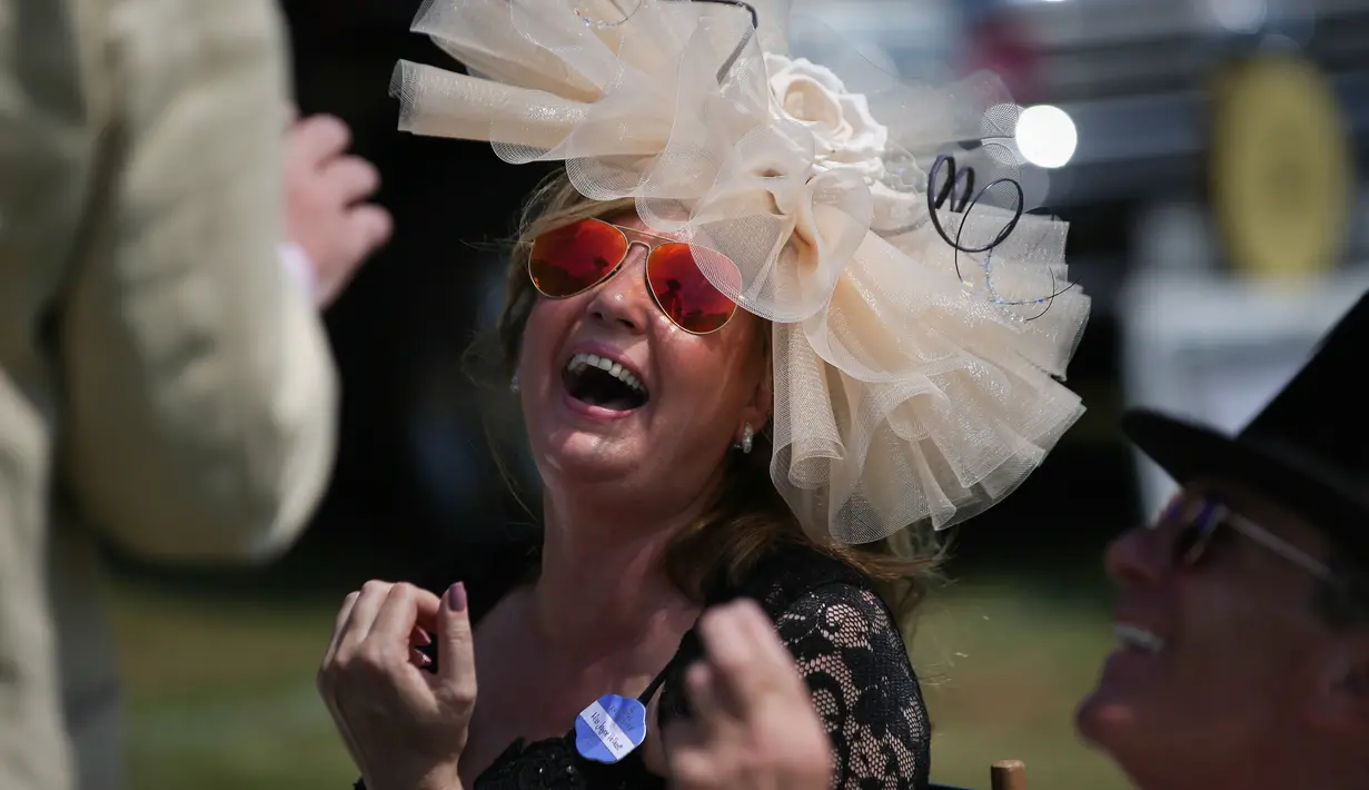 Seorang wanita tertawa saat makan siang di tempat parkir menjelang balap kuda di Ascot, London, (20/6). Mereka tampil gaya saat menyaksikan kompetisi balap kuda ini. (AFP Photo/Daniel Leal-Olivas)