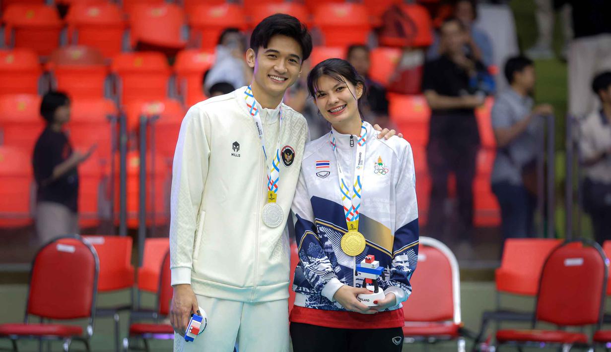 Pevoli Indonesia Alfin Daniel Pratama (kiri) berfoto bersama dengan kekasihnya yang juga penerjemah Timnas voli putra Thailand, McEntee Catherine, di Stadion Indoor Hua Mak, Jumat (19/12/2025). Pasangan pevoli Indonesia, Alfin Daniel Pratama dan penerjemah timnas voli putra Thailand, McEntee Catherine kedapatan saling memberikan dukungan usai laga sengit final voli putra SEA Games 2025 di Stadion Indoor Hua Mak, Jumat (19/12/2025). (Bola.com/Bagaskara Lazuardi)