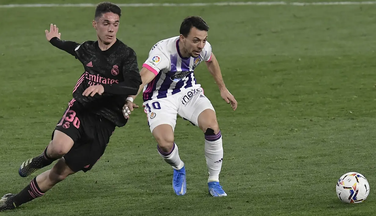 Pemain Real Valladolid, Oscar Plano, berebut bola dengan pemain Real Madrid, Sergio Arribas, pada laga Liga Spanyol di Stadion Jose Zorrila, Minggu (21/2/2021). Real Madrid menang dengan skor 1-0. (AP/Alvaro Barrientos)