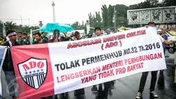 Massa Asosiasi Driver Online (ADO) membentangkan spanduk di depan Istana, Jakarta, Senin (19/9). Dalam aksinya, mereka menolak diberlakukan ujian kendaraan bermotor (KIR) menggunakan SIM A UMUM per 1 Oktober 2016. (Liputan6.com/Faizal Fanani)