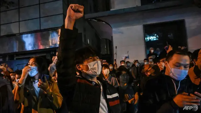 Orang-orang menyanyikan slogan saat berkumpul di sebuah jalan di Shanghai pada 27 November 2022. (Foto: AFP/Hector Retamal)