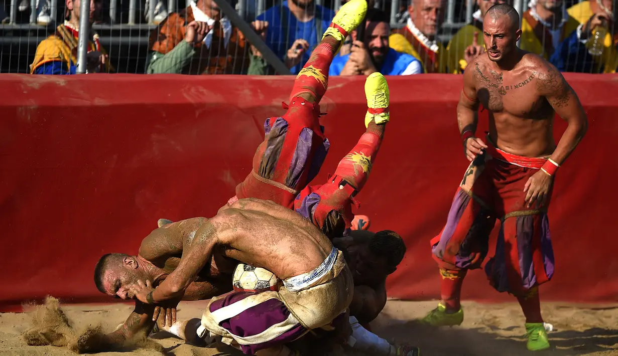 Pemain bergulat memperebutkan bola saat pertandingan Calcio Storico Fiorentino di Piazza Santa Croce di Florence, Italia (24/6). Satu tim terdiri dari 27 atlet dan tidak ada pergantian pemain selama pertandingan. (AFP Photo/Filippo Monteforte)
