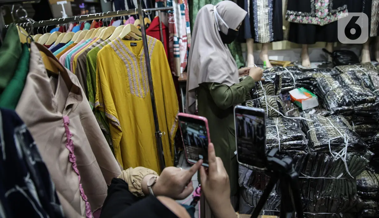 Pedagang menjualkan pakaian melalui melalui aplikasi online di Pasar Tanah Abang, Jakarta, Rabu (1/7/2020). Pedagang di Pasar Tanah Abang mulai menjual barang secara daring untuk menambah penjualan dan mengantisipasi turunnya jumlah pembeli di masa PSBB Transisi ini. (Liputan6.com/Faizal Fanani)