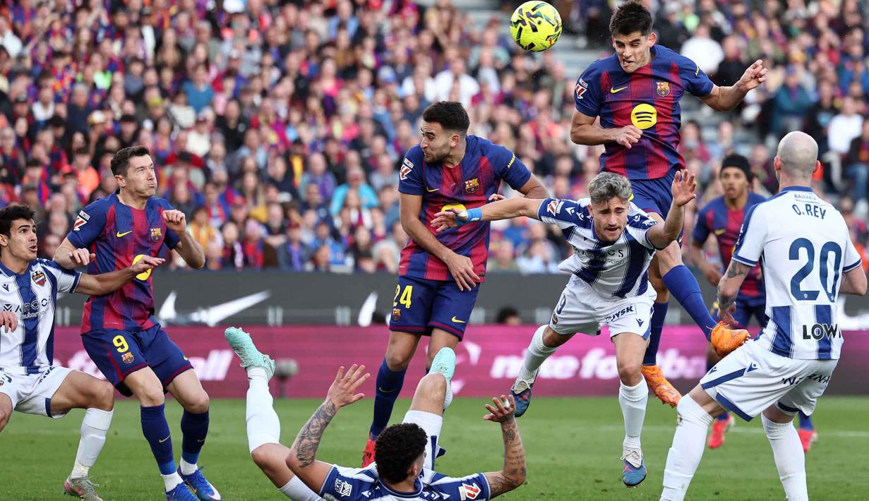 Skor 2-0 untuk keunggulan Barcelona bertahan hingga babak pertama usai. Tampak dalam foto, bek Barcelona asal Spanyol, Gerard Martin (atas), menyundul bola selama pertandingan pekan ke-25 La Liga 2025/2026 melawan Levante UD di Stadion Camp Nou, Minggu 22 Februari 2026. (Josep LAGO/AFP)
