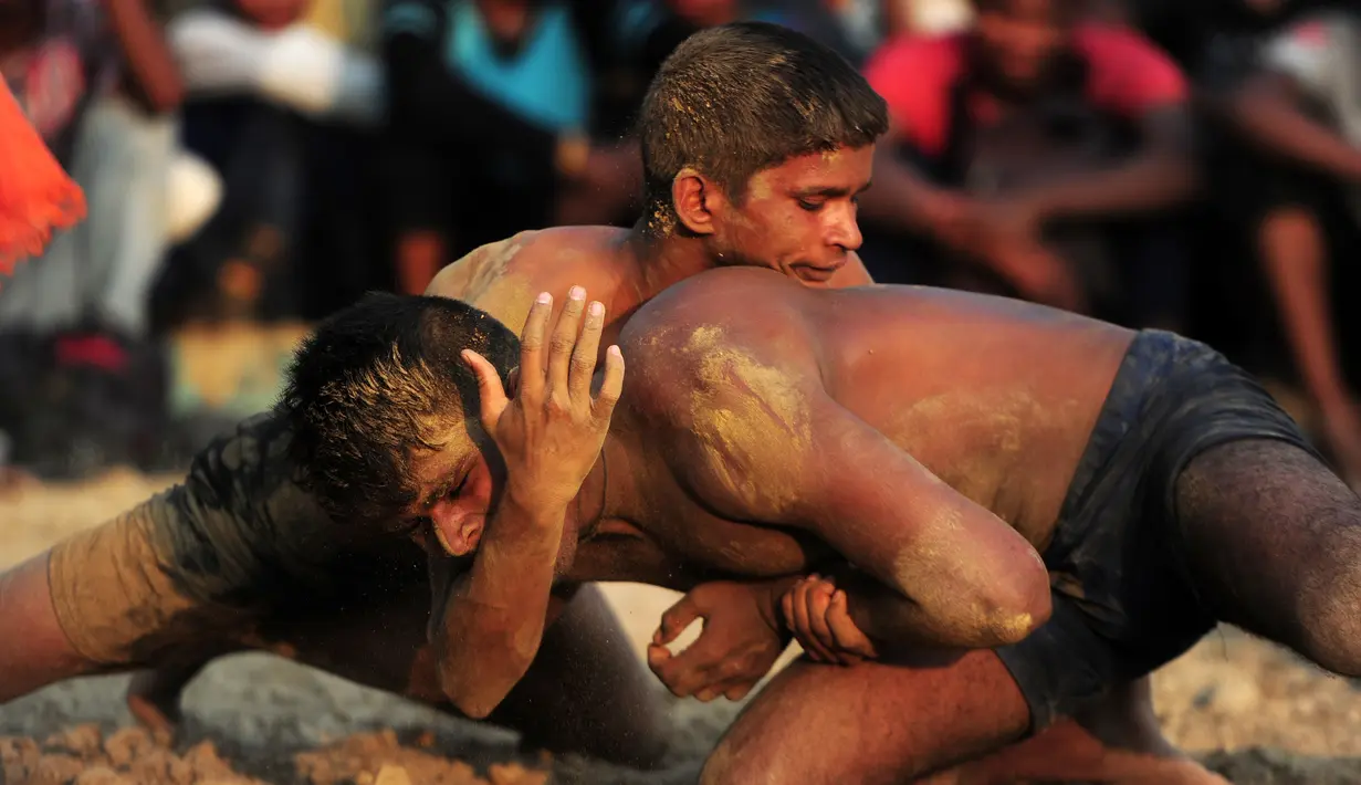 Pegulat melakukan gerakan kuncian saat mengikuti kompetisi gulat tradisional India yang diadakan di desa Rampur, India (7/10). Olahraga tradisional ini terus di lestarikan sebagai bagian dari budaya India. (AFP Photo/Sanjay Kanojia)