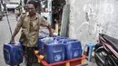 Pedagang mengantarkan air pikulan kepada warga di kampung nelayan Kalibaru, Cilincing, Jakarta Utara, Selasa (22/3/2022). Hingga kini air pikulan masih menjadi kebutuhan utama warga di kawasan pesisir Cilincing untuk keperluan konsumsi akibat air sumur keruh dan bau. (merdeka.com/Iqbal S Nugroho)