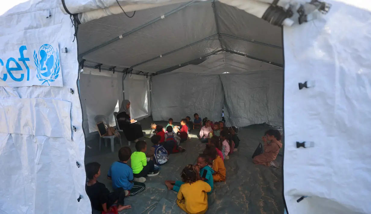 Beberapa guru Palestina memberikan pendidikan dasar di sekolah darurat yang didirikan oleh Asosiasi Kebudayaan Mayasem dengan dukungan UNICEF di kamp pengungsian di kawasan al-Qarara, Khan Yunis, di bagian selatan Jalur Gaza pada Selasa 7 Oktober 2025. (Omar AL-QATTAA/AFP)