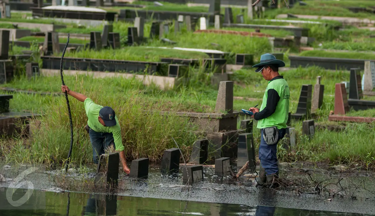 Petugas mengukur tinggi air di area Tempat Pemakaman Umum (TPU) Tanah Kusir, Jakarta, Selasa (25/4). Di TPU Tanah Kusir ini karena kerap tergenang banjir ketika terjadi hujan lebat. (Liputan6.com/Gempur M. Surya)