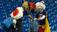 Suporter timnas Jepang mengumpulkan sampah setelah laga 16 besar Piala Dunia 2018 melawan Begia di Rostov Arena, Senin (2/7). Meski timnya tersingkir secara dramatis, tak menghalangi para suporter Jepang melakukan aksi positif. (AFP/JUAN BARRETO)