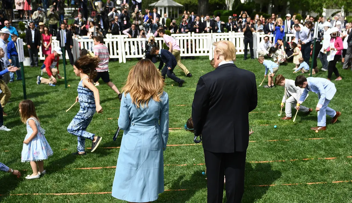 Presiden AS Donald Trump dan Ibu Negara Melania Trump menyaksikan anak-anak menggelindingkan telur paskah di South Lawn Gedung Putih, Washington, Senin (22/4). Acara tahunan itu merupakan bagian dari rangkaian memperingati Paskah yang rutin diselenggarakan Gedung Putih. (Brendan Smialowski/ AFP)