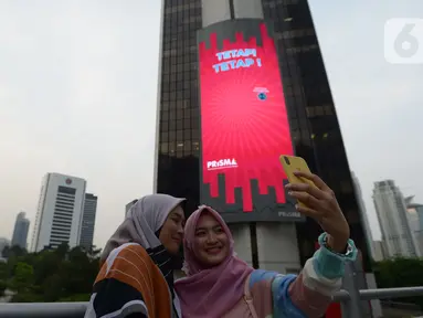 Warga berselfie di kawasan jalan Jenderal Sudirman, Jakarta,Sabtu (18/7/2020). Pemerintah Provinsi DKI Jakarta memperpanjang PSBB fase transisi selama 14 hari hingga 30 Juli, seiring kasus baru COVID-19 masih tinggi di ibu kota. (merdeka.com/Imam Buhori)