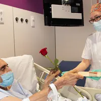 Seorang perawat memberikan buku dan bunga mawar kepada pasien yang dirawat di sebuah rumah sakit pada Hari Saint George di Barcelona, Spanyol (23/4/2020). (Xinhua/Francisco Avia)