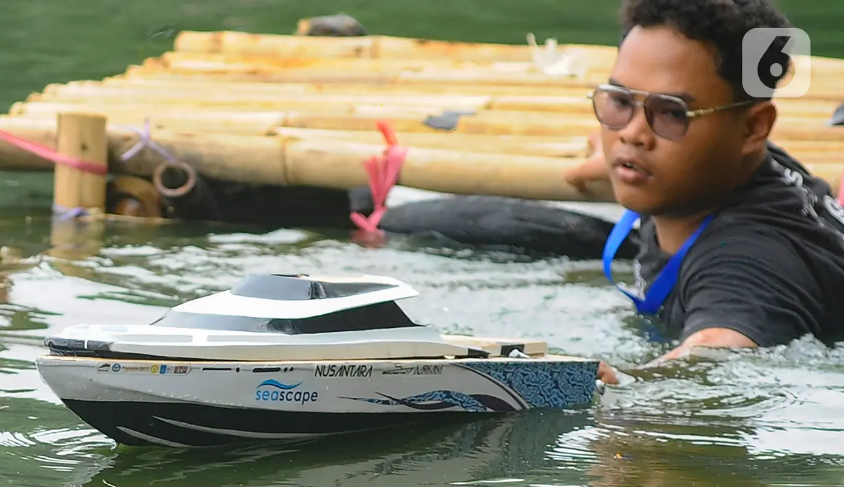 Seorang mahasiswa mendorong kapal cepat tak berawak ke tengah danau saat mengikuti Kontes Kapal Cepat Tak Berawak Nasional (KKCTBNdi Danau Kenanga, Kampus UI, Depok, Jawa Barat, Selasa (24/10/2023). (merdeka.com/Arie Basuki)