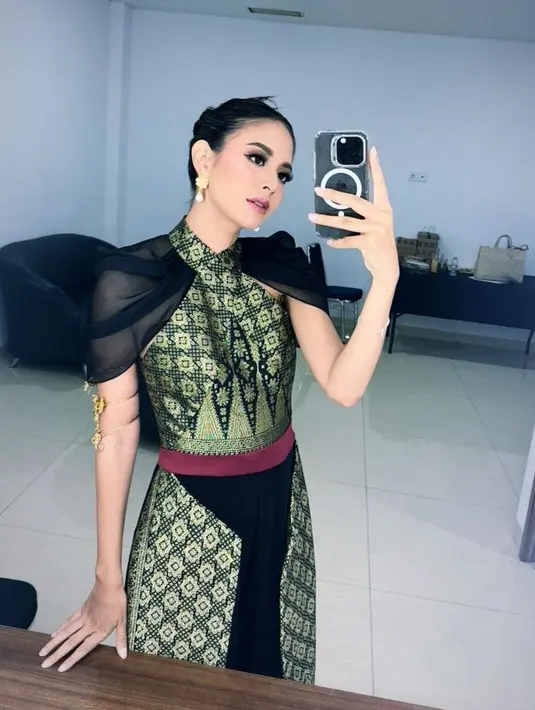 Aurelie hadir mengenakan dress cross neck model songket yang didominasi warna hijau, dengan akses organza hitam pada bagian pundak. [@aurelie]