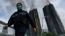 Merujuk data sensus pemerintah tahun 2021, dengan 1.984 apartemen ada sekitar 4.600 penduduk tinggal di sana. Tampak dalam foto, seorang petugas polisi berjalan melewati lokasi kebakaran di Wang Fuk Court, sebuah kompleks perumahan di distrik Tai Po, Wilayah Baru Hong Kong, Kamis 27 November 2025. (AP Photo/Chan Long Hei)
