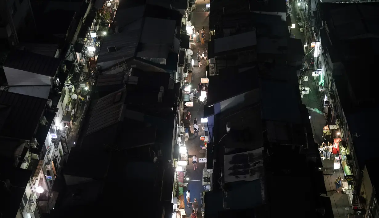 Orang-orang berjalan melalui gang-gang sempit yang dikelilingi bar dan restoran kecil di Golden Gai di distrik Shinjuku Tokyo (28/7/2019). Kawasan Ini terdiri dari enam jalanan sempit yang menghubungkan lorong yang lebih sempit yang hanya cukup dilewati satu orang. (AP Photo/Jae C.Hong)