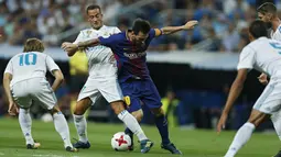 Aksi Lionel Messi (tengah saat mencoba melewati adangan para pemain Real Madrid pada leg kedua Piala Super Spanyol di Santiago Bernabeu stadium (16/8/2017). Real menang 2-0. (AP/Francisco Seco)