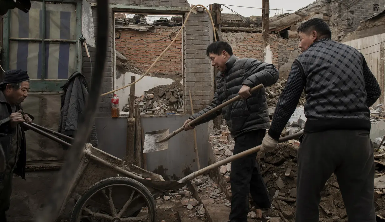 Para pekerja memuat puing-puing dari rumah yang hancur ke atas gerobak dorong ketika mereka memperbarui sebuah daerah di daerah hutong di Beijing (26/2). (AFP Photo/Nicolas Asfouri)