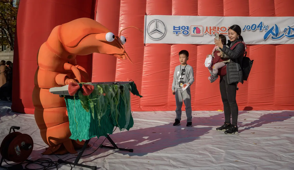 Pengunjung mengabadikan orang berpakaian udang selama festival pembuatan kimchi di Seoul (2/11). Festival pembuatan kimchi ini menandai awal musim dingin. (AFP Photo/Ed Jones)
