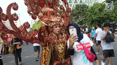 Seorang warga yang tengah mengikuti Car Free Day (CFD) berswafoto dengan peserta Parade Asian Games 2018 2018 di Jalan Thamrin, Jakarta, Minggu (13/5). Tak merasa terganggu, mereka justru ikut antusias menyaksikan parade itu. (Liputan6.com/Arya Manggala)