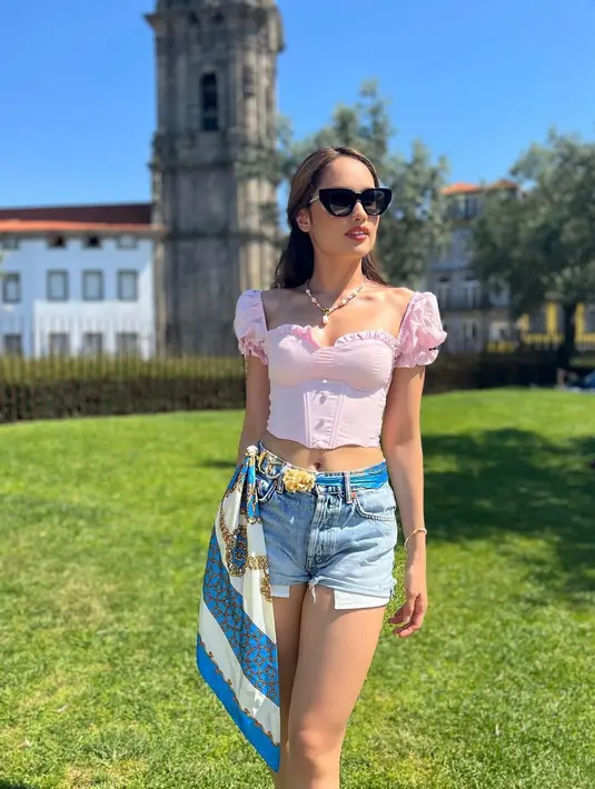 Mengenakan busana berwarna pink dan celana jeans pendek serta kaca mata hitam, Cinta Laura tampil cantik saat berpose di dekat menara Menara Clérigos, Porto, Portugal. (Instagram/claurakiehl)