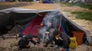 Anak-anak pengungsi yang melarikan diri bersama keluarga mereka dari serangan artileri Israel di Lebanon selatan membuat api unggun di samping tenda yang digunakan sebagai tempat berlindung di Beirut, Lebanon, Rabu, 1 April 2026. Di tengah meningkatnya serangan udara Israel, gelombang pengungsi di Lebanon terus bertambah. (AP Photo/Emilio Morenatti)