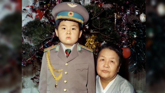 Kim Jong-Nam kecil mengenakan seragam tentara berpose dengan nenek dari pihak ibu pada Januari 1975. Kakak tiri Kim Jong-un, Kim Jong-nam, tewas dalam sebuah serangan di Bandara Internasional Kuala Lumpur pada 13 Februari 2017. (AFP PHOTO)