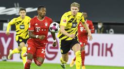 Pemain Bayern Munchen, David Alaba, berebut bola dengan striker Borussia Dortmund, Erling Haland, pada laga Bundesliga di Stadion Signal Iduna Park, Sabtu (7/11/2020). Bayern menang dengan skor 3-2. (Bernd Thissen/Pool via AP)
