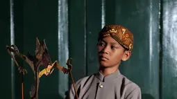 Seorang anak berpose dengan memegang sebuah wayang selama festival Dalang Bocah di Kawasan Kota Tua, Jakarta (20/11).  Festival akan berlangsung dari 20-22 November 2015. (Liputan6.com/Gempur M Surya)