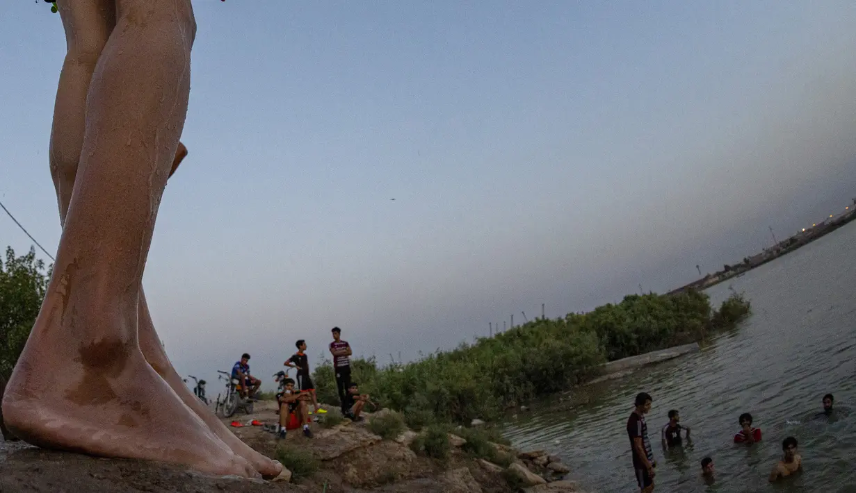 Seorang pemuda bersiap untuk terjun ke Sungai Shatt Al-Arab di Kota Basra, Irak, Selasa (9/6/2020). Sungai yang memiliki panjang sekitar 200 Km ini menandai perbatasan antara Irak dan Iran. (Hussein FALEH/AFP)