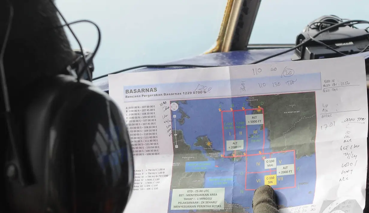 Seorang awak pesawat mengamati peta rencana pergerakan Basarnas saat melakukan pencarian pesawat AirAsia QZ8501, Senin (29/12/2014). (Liputan6.com/Herman Zakharia)