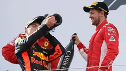 Pembalap Red Bull Max Verstappen meminum sampanye bersama dengan pembalap Ferrari, Sebastian Vettel dari Australia setelah berhasil memenangkan GP Austia di Red Bull Ring, Spielberg, Austria, (1/7). (AP Photo / Ronald Zak)