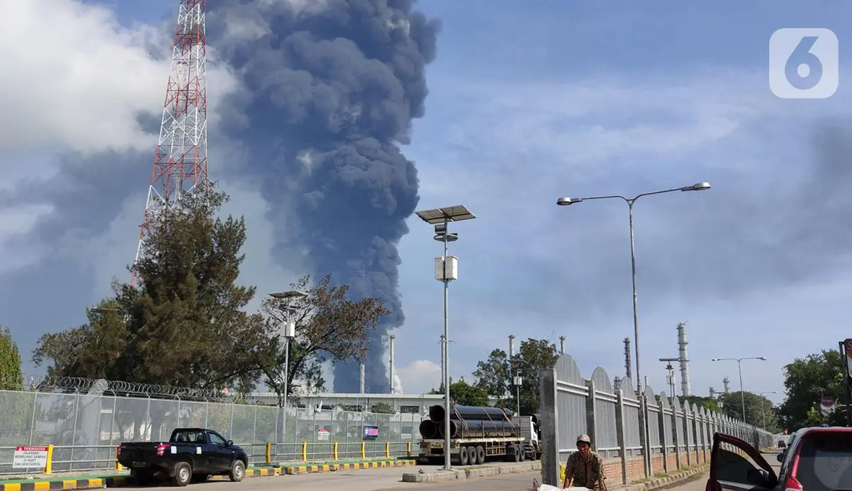 Photo)
Kepulan asap hitam masih terlihat di Kilang Pertamina Balongan Indramayu yang terbakar, Senin (29/3/2021). Di lokasi, petugas gabungan nampak menutup jalan berupa jalur dari Cirebon menuju Indramayu arah Balongan.  (Liputan6.com/Panji Prayitno)