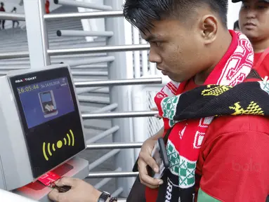 Seorang suporter menempelkan tiket ke mesin barcode saat memasuki SUGBK, Senayan, Jakarta, Minggu (14/1/2018). Fasilitas baru tersebut untuk meningkatkan keamananan, kenyamanan serta kedisiplinan suporter. (Bola.com/M Iqbal Ichsan)