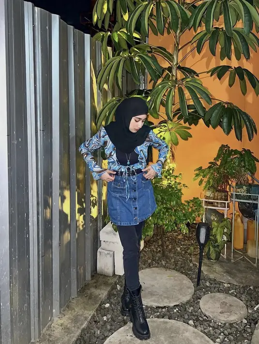 Ia mengenakan atasan lengan panjang warna biru dipadukan rok denim pendek dan celana hitam yang serasi dengan kerudung serta bootsnya.  Credit: Instagram @osnapitzcha