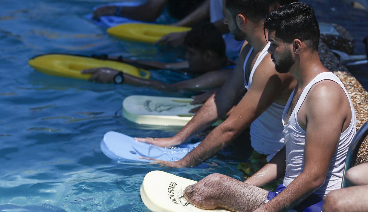 Pemuda Palestina mengikuti pelatihan renang oleh instruktur Majdi al-Tatar di Kota Gaza (30/7/2019). Tatar melatih warga Palestina yang diamputasi untuk membantu mereka mempertahankan aktivitas fisik. (AFP Photo/Mahmud Hams)