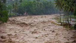 Data Pusat Pengendalian Operasi Penanggulangan Bencana (Pusdalops) BPBD Padang, Kecamatan Koto Tangah menjadi wilayah dengan jumlah terdampak terbesar, yaitu 20.983 warga. Tampak dalam foto, warga bertahan di tepi sungai saat banjir melanda Padang, Provinsi Sumatra Barat, pada Kamis 27 November 2025. (REZAN SOLEH/AFP)
