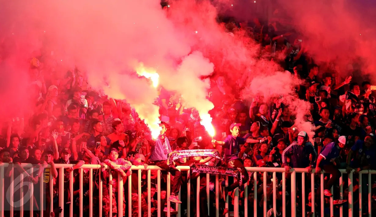 Suporter Arema FC menyalakan suar dan bersorak saat merayakan kemenangan atas PBFC di final Piala Presiden 2017 di Stadion Pakansari, Kab Bogor, Minggu (12/3). Arema FC juara Piala Presiden 2017. (Liputan6.com/Helmi Fithriansyah)