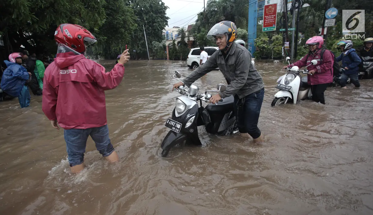 Para pengendara mendorong motornya saat melintasi banjir di Jalan Boulevard Barat Raya, Kelapa Gading, Jakarta, Kamis (15/2). Hujan lebat sejak pagi hingga sore hari mengakibatkan sejumlah wilayah Ibu Kota terendam banjir. (Liputan6.com/Arya Manggala)