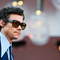 Penyanyi dan aktor Inggris Harry Styles tiba untuk pemutaran perdana film 'Don't Worry Darling' selama Venice Film Festival 2022 di Venesia, Italia, Senin (5/6/2022). Harry Styles juga memakai kacamata hitam Gucci berukuran sama dengan nuansa Elton John dari koleksi yang sama. (Photo by Tiziana FABI / AFP)