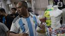 Seorang pria mencoba jersey Argentina tim peserta Piala Dunia 2022 Qatar di salah satu kios di Blok B Pasar Tanah Abang, Jakarta, Jumat (18/11/2022). Jersey sejumlah tim nasional favorit peserta Piala Dunia 2022 Qatar seperti Belanda, Brasil, Jerman, serta Argentina banyak diburu pembeli. (Liputan6.com/Faizal Fanani)