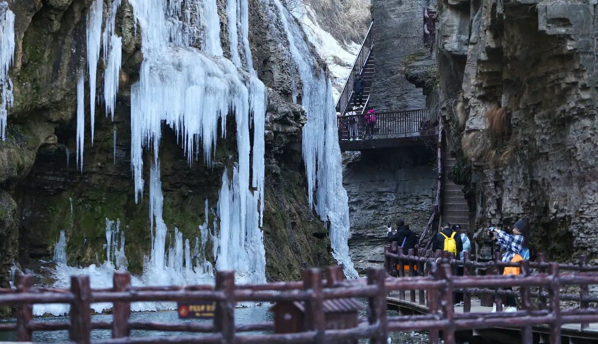 Sejumlah pengunjung menikmati pemandangan air terjun beku di objek wisata Gunung Yuntai di Jiaozuo, Provinsi Henan, China tengah, pada 24 Desember 2020. (Xinhua/Xu Yanan)