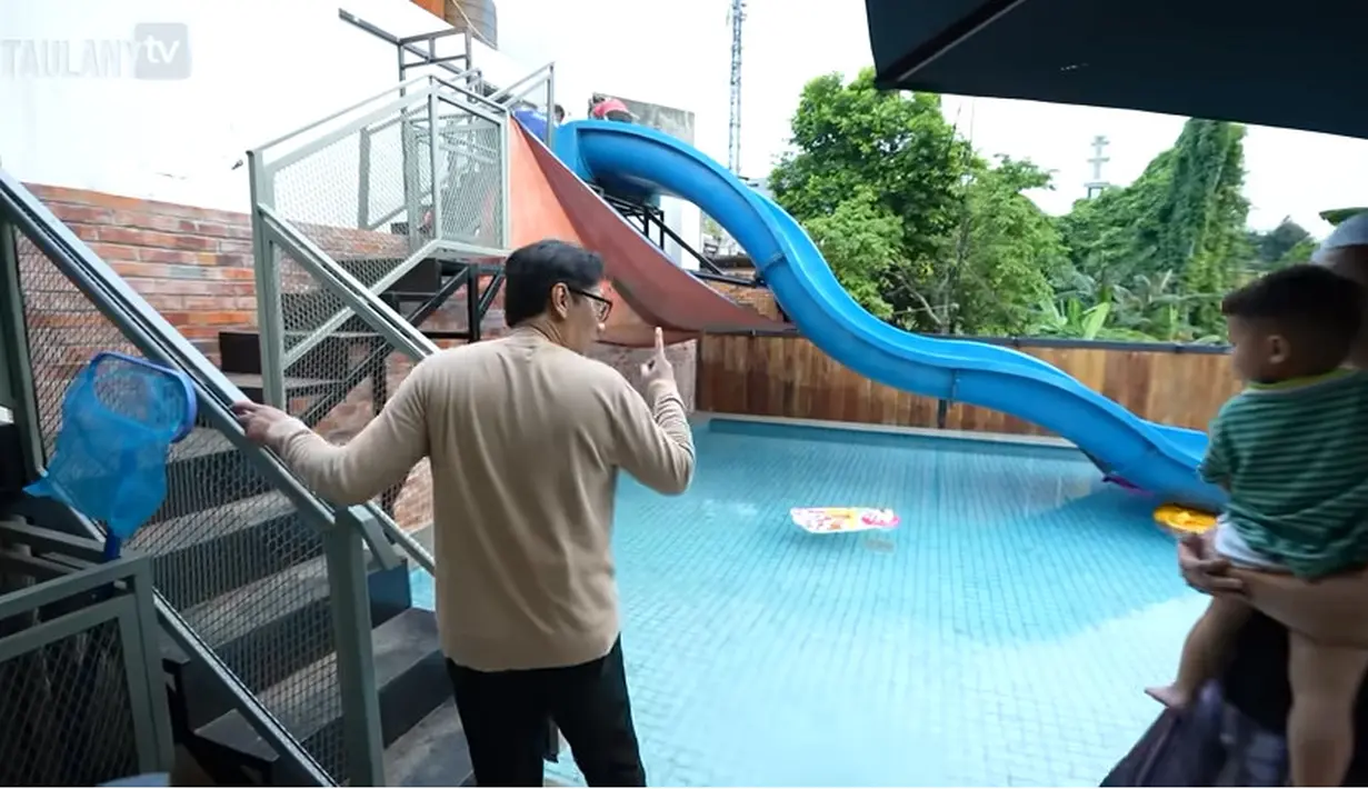 Keluar kantor, terdapat kolam renang yang sangat panjang dengan dengan perosotan panjang. Dari tangga ini juga bisa masuk ke kantor yang berada di lantai dua. [Youtube/TAULANY TV]