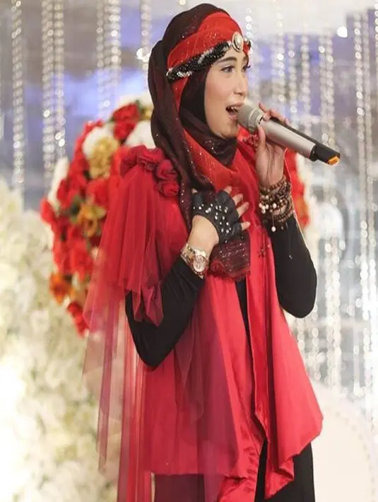 Tampil menyumbangkan suara emasnya dalam acara pernikahan rekannya, Inka Christie tampil dengan gaya pakaian hijab merah dan hitam lengkap dengan hiasan khas penyanyi rock (Liputan6.com/Instagram/@inka_christie99)