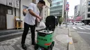 <p>Seorang karyawan restoran menempatkan pesanan makanan di dalam robot tanpa awak selama uji coba layanan pengiriman robot oleh Uber Eats Japan, Mitsubishi Electric dan pengembang robot Cartken di pusat kota Tokyo pada tanggal 5 Maret 2024. (Richard A. Brooks/AFP)</p>