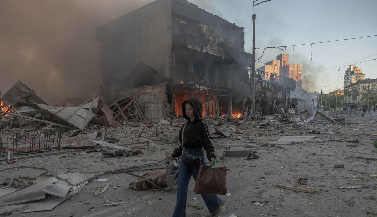 Seorang wanita berjalan di samping bangunan-bangunan yang rusak parah akibat serangan Rusia di Kyiv pada Minggu 24 Mei 2026, di tengah invasi Rusia ke Ukraina. (Roman PILIPEY/AFP)