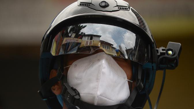 Sukarelawan petugas kesehatan dari LSM India Bharatiya Jain Sanghatana mengenakan helm pintar untuk melakukan screening kasus COVID-19 dari pintu ke pintu di Mumbai, 21 Juli 2020. Alat tersebut memungkinkan petugas Kesehatan mencatat suhu puluhan penduduk per menit. (INDRANIL MUKHERJEE/AFP)