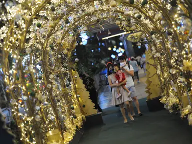 Orang-orang berfoto dengan dekorasi lampu Natal di tengah hujan rintik di sepanjang pusat perbelanjaan Orchard Road di Singapura (16/12/2020). Distrik perbelanjaan utama Singapura di Orchard Road mulai bersinar diwarnai oleh hiasan dan dekorasi natal. (Xinhua/Then Chih Wey)
