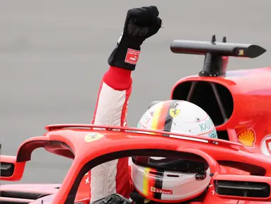 Pembalap Ferrari, Sebastian Vettel mengangkat tangannya saat merayakan kemenangannya di Formula1 Grand Prix (GP) di Montreal, Kanada, Minggu (10/6). Vettel sukses meraih podium juara. (Tom Boland/The Canadian Press via AP)