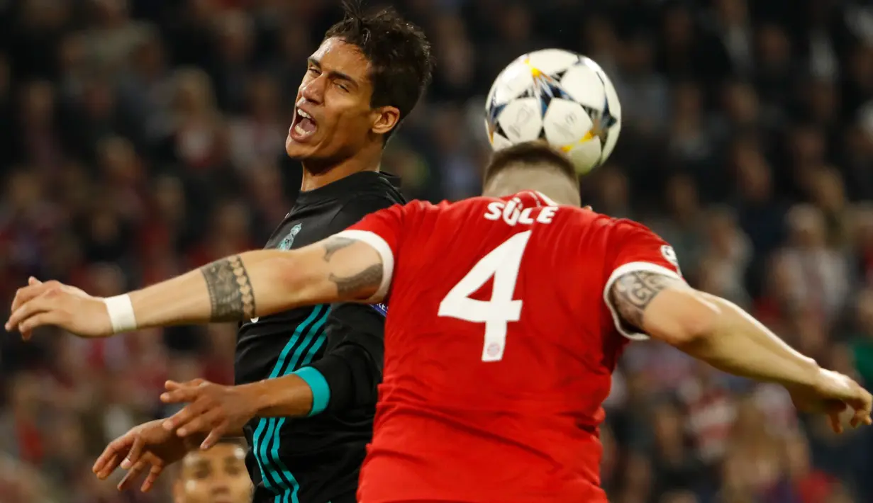 Bek Bayern Munchen, Niklas Suele berebut bola dengan pemain Real Madrid, Raphael Varane pada leg pertama semifinal Liga Champions di Allianz Arena, Rabu (25/4). Real Madrid meraih kemenangan 2-1 saat bertandang ke markas Bayern Munchen. (Odd ANDERSEN/AFP)